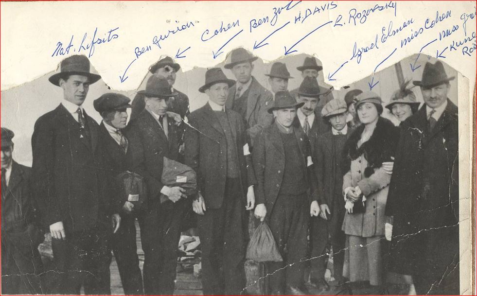Groupe de 12 hommes et deux femmes (les hommes en complet et chapeau ou casquette, les femmes portant un manteau et un chapeau).
