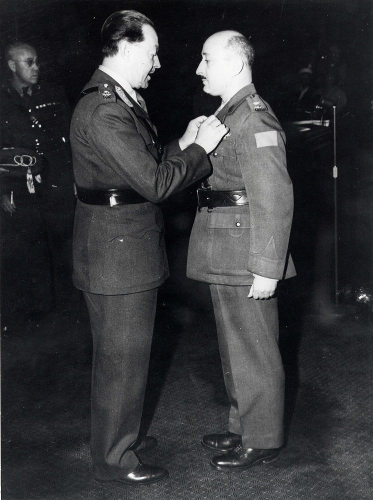 Deux hommes en uniforme de l’Armée canadienne, celui de droite recevant une médaille de la part de celui de gauche.