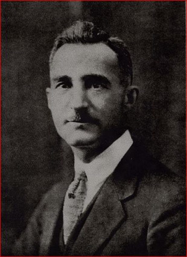 Portrait officiel d’un homme portant une moustache et un costume.