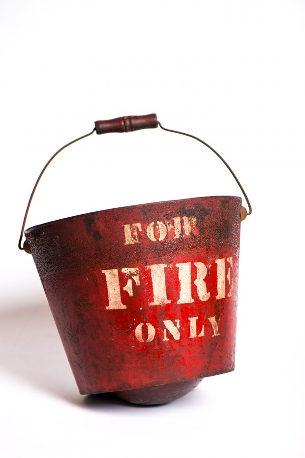 Photographie d’un seau d’incendie à fond rond de couleur rouge où les lettres moulée blanches indiquent en anglais For Fire Only.