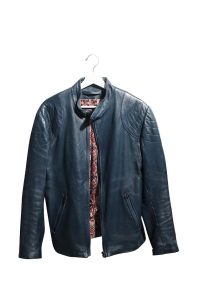 Une veste en cuir bleu foncé sur un cintre blanc. La veste est légèrement ouverte, révélant une doublure colorée.