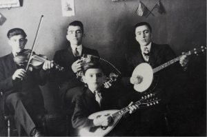Black and white photograph of the Orchestre Montminy. The band consisted of Réal Montminy (fiddle), Joseph Montminy (accordion), Gérard Montminy (banjo) and their little brother Bertrand (mandolin). All the musicians are dressed up in suits and ties.