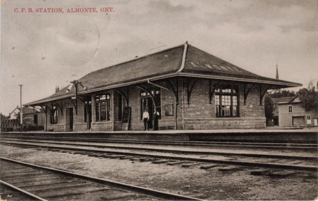Carte postale photographique noir et blanc de la gare d’Almonte montrant la voie ferrée à l’avant-plan, années 1950