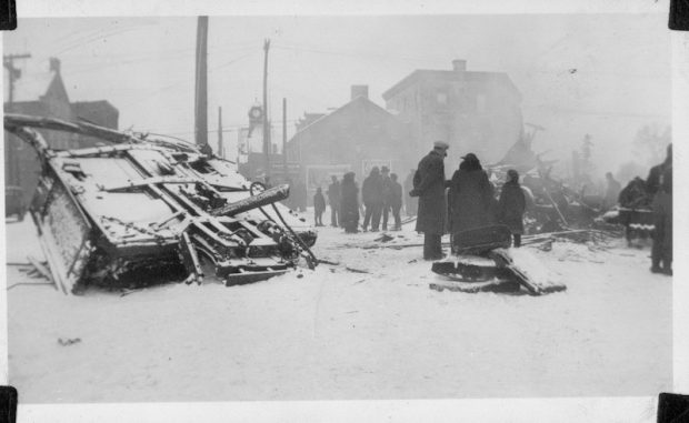 Photographie des décombres de la troisième voiture du train local de la vallée de l’Outaouais, à Almonte; on voit des gens qui marchent dans la ville, 1942