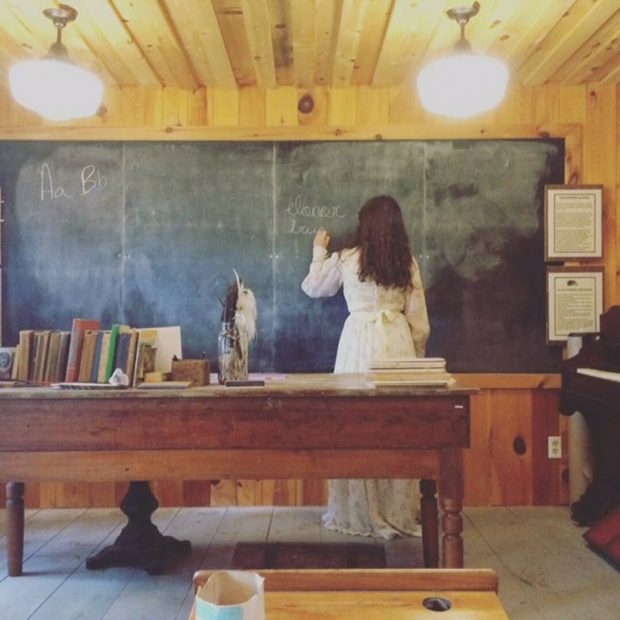 Un professeur écrit sur un tableau noir dans une maison en bois.