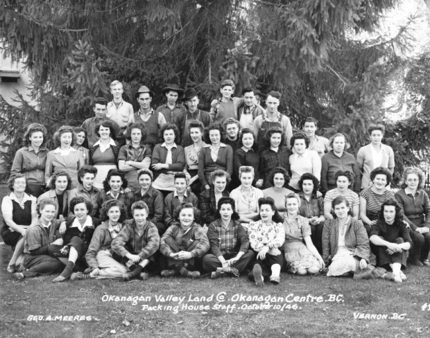 Photo extérieure en noir et blanc représentant 36 femmes et 10 hommes sur quatre rangées : deux rangées debout et deux assises; les hommes sont à l’arrière. Un grand conifère se dresse derrière le groupe.