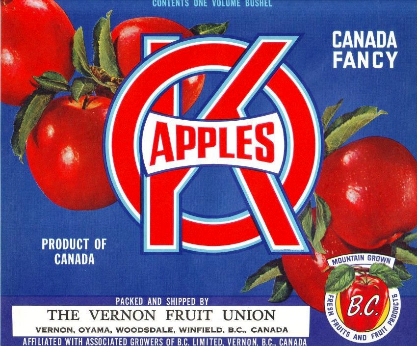 Photo en couleur d’une étiquette de caisse de pommes de la marque OK. L’étiquette comprend une inscription de couleur rouge et blanche, et cinq pommes rouges sur fond bleu.