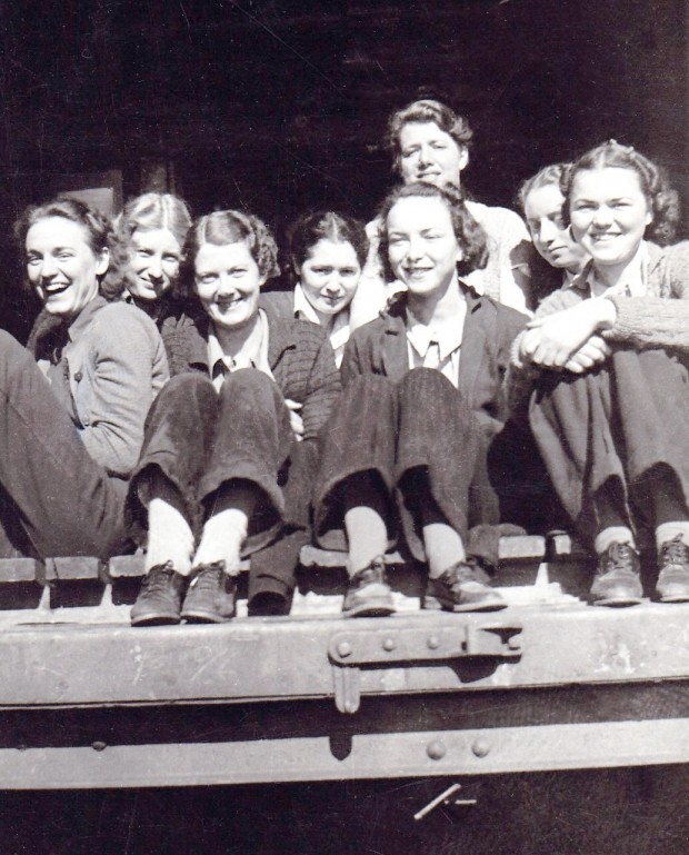 Photo en noir et blanc représentant huit femmes assises à l’entrée d’une rampe de chargement.