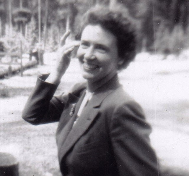 Portrait spontané en noir et blanc d’une femme souriante en train de marcher.