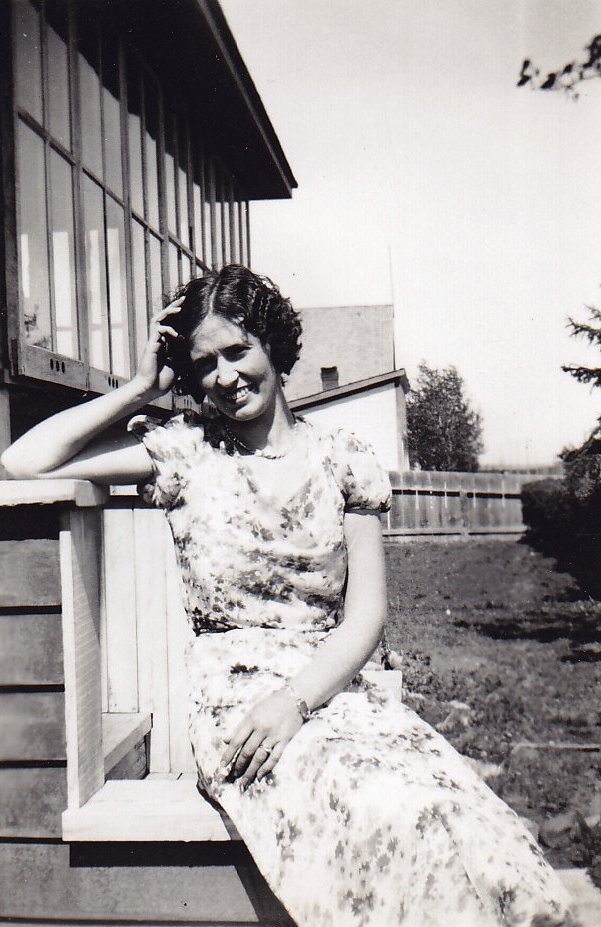Photo en noir et blanc d’une jeune femme portant une robe à fleur assise sur les marches d’un édifice.