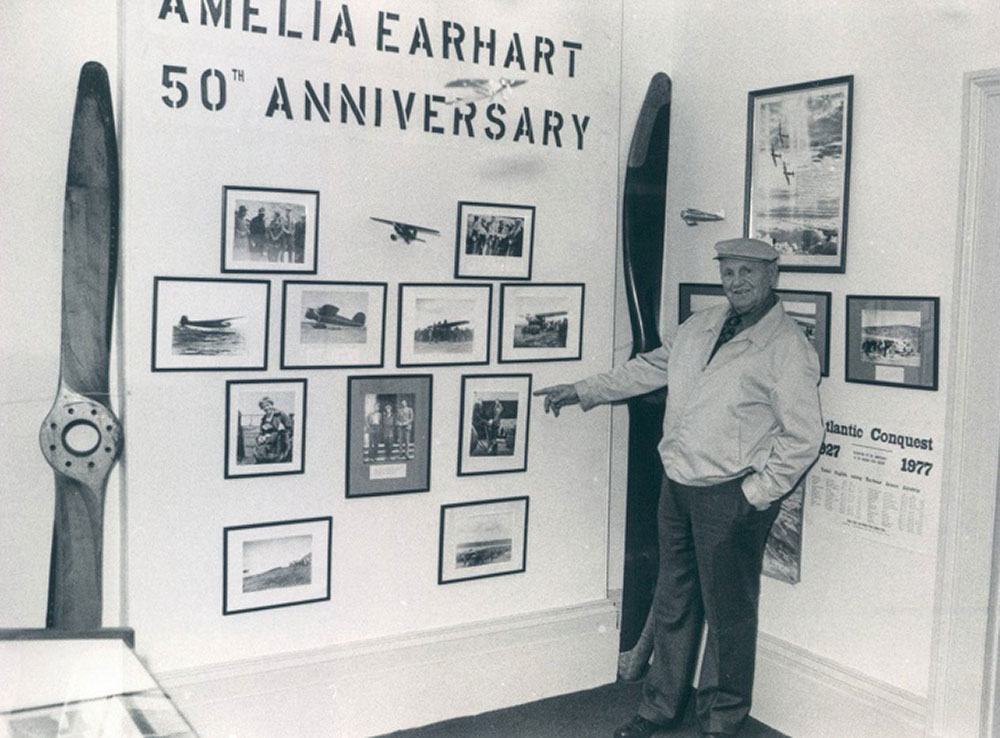 Photographie en noir et blanc de Bill Parsons qui montre des photos d’Amelia Earhart exposées au Conception Bay Museum. Deux hélices d’avion sont exposées dans la salle.