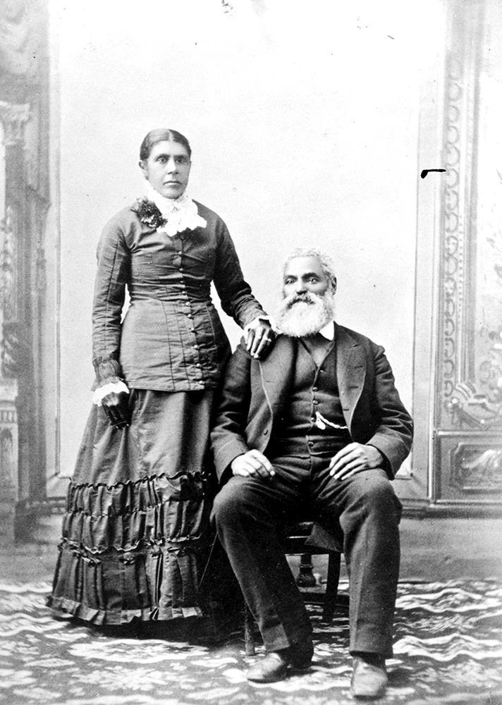 portrait studio professionnel en noir et blanc : une femme est debout à côté d’un homme assis. Les cheveux de Nancy sont séparés au centre, puis repliés en chignon. Sa main droite repose sur l’épaule de son mari. Charles, assis à sa droite, le pied droit légèrement en avant, porte un costume et un gilet foncés et exhibe une chaîne de montre hors de la poche de son gilet. Il a les cheveux blancs, une moustache et une barbe pleine