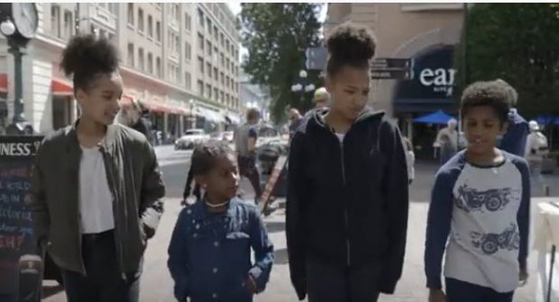 quatre jeunes, âgés de 6 à 15 ans, marchant côte à côte dans le square historique