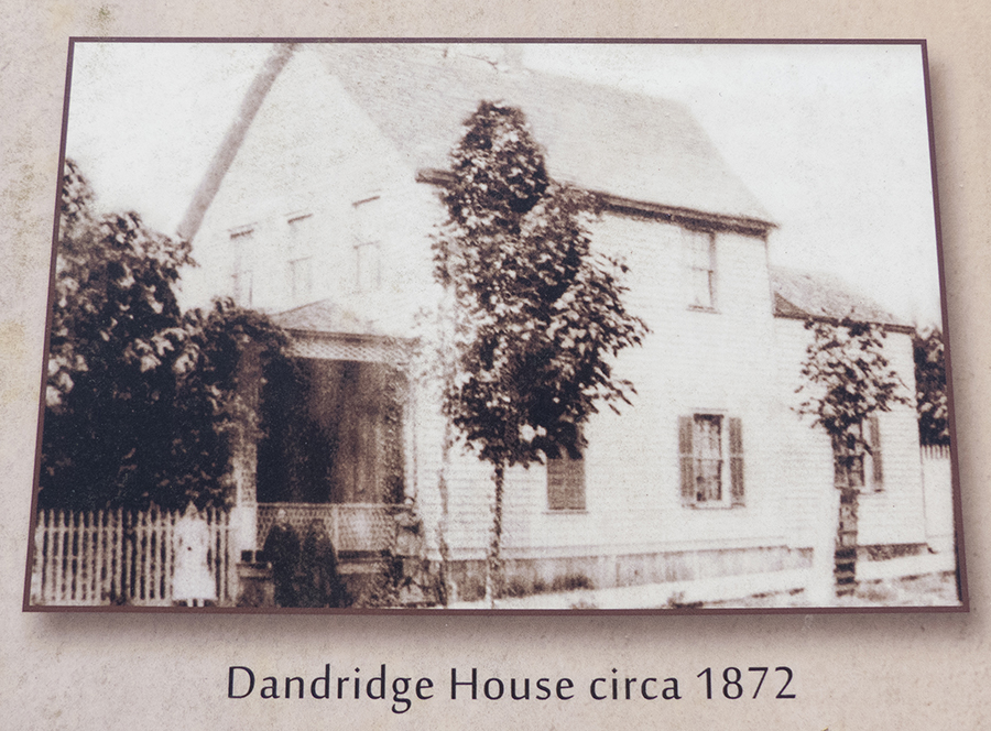 Sépia réalisé sous l’angle latéral de la maison de deux étages à pignons et bardeaux avec véranda, clôture et arbres à l’avant