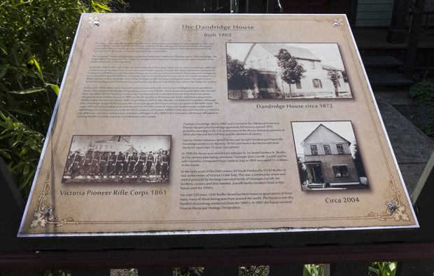 Un texte et trois images figurent sur une plaque commémorative apposée sur une clôture à un angle faible permettant de la voir de la rue