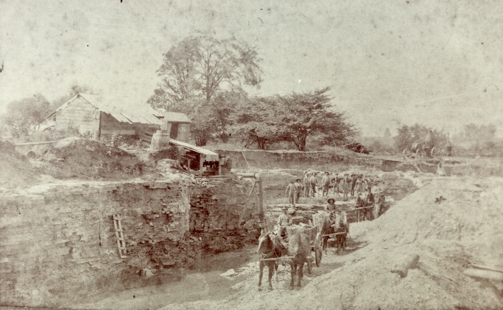Image en noir et blanc d’un équipage d’ouvriers, de chevaux et de charrettes dans une carrière