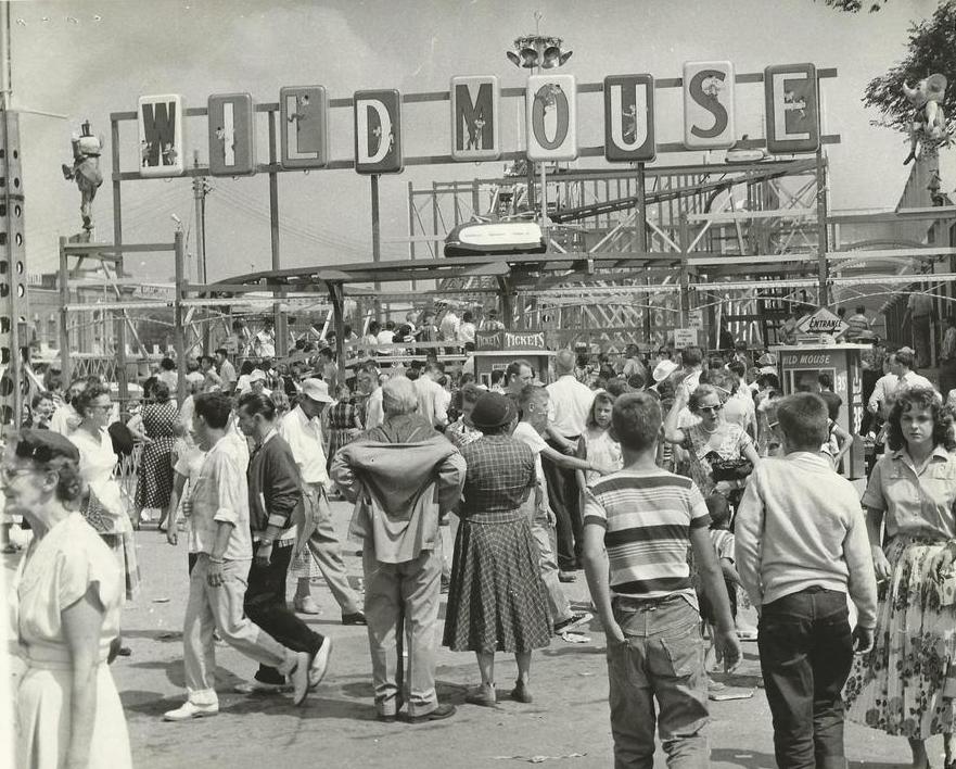 Une photo en noir et blanc d’une fête foraine bondée de monde avec la montagne russe Wild Mouse