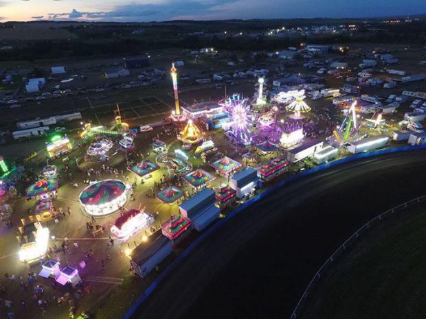 Vue de haut d’une fête foraine dont les lumières brillent dans le ciel nocturne