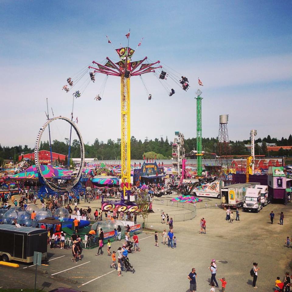 Une vue d’ensemble des attractions de la fête foraine montées dans un stationnement, le manège Vertigo est au centre