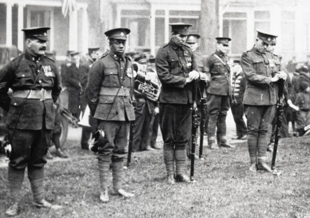 Photo d’archives en noir et blanc d’anciens combattants de la Première Guerre mondiale debout en rangs, un soldat noir regardant l’appareil photo. 