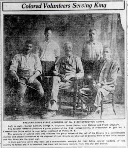 Coupure de presse avec l’image de cinq hommes noirs, trois assis sur des chaises en bois et deux debout.
