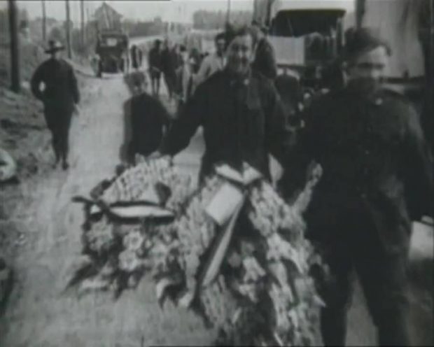 Deux hommes en uniforme militaire transportent des couronnes funéraires.