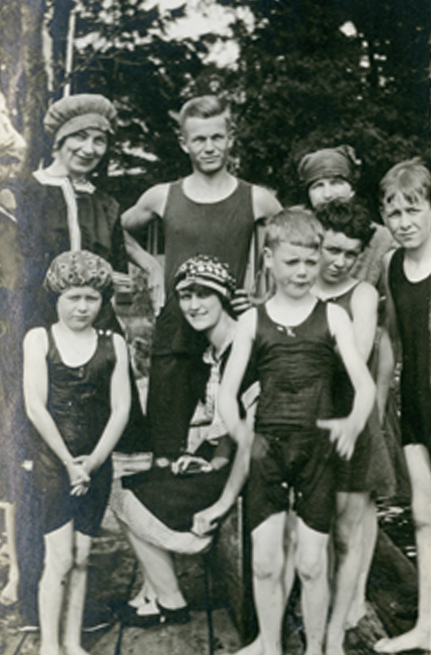 Un groupe composé surtout d’enfants en maillot de bain se tient sur un quai.