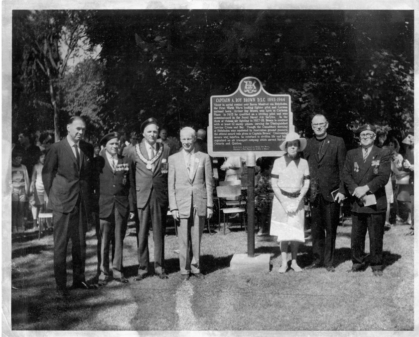 Un groupe de personnes devant une grande plaque.