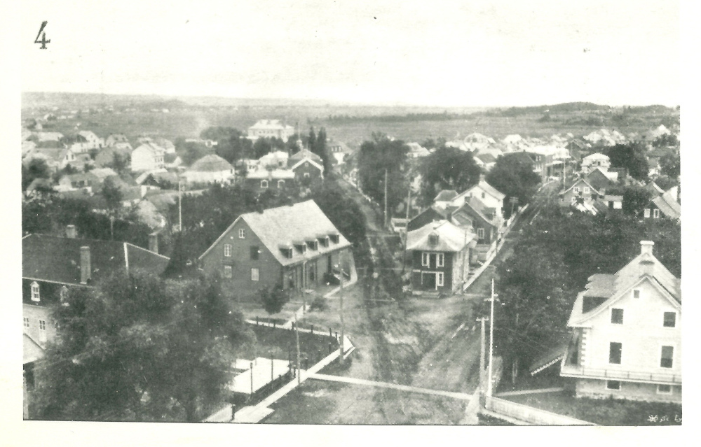 Photographie noir et blanc du village de Montmagny, des maisons de bois aux toits pentus bordent les rues.