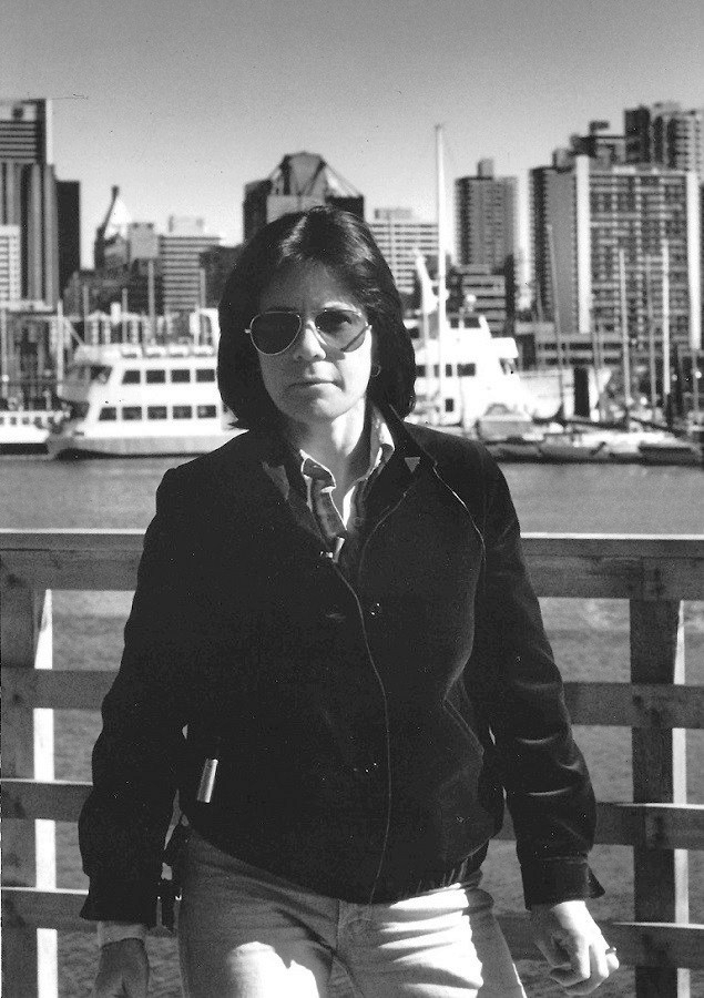 Photo en noir et blanc de Mary Anne McEwen sur le front de mer de Vancouver avec la ville derrière elle, vers 1983.