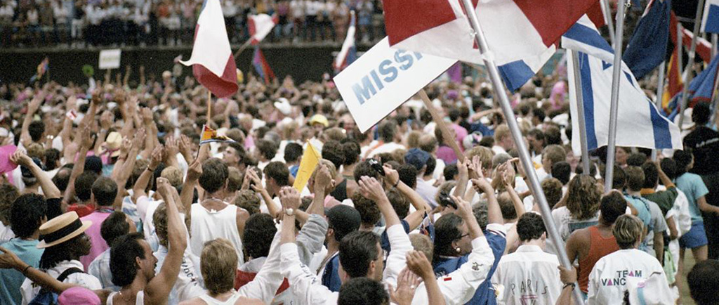 Des foules d'athlètes et d'autres participants, agitant divers drapeaux nationaux lors de la cérémonie d'ouverture de la célébration 90.