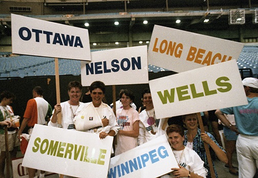  Un groupe d'athlètes féminines canadiennes tient des pancartes avec le nom de leur ville natale sur le sol de la Colombie-Britannique. Placez le stade pendant les cérémonies de clôture.