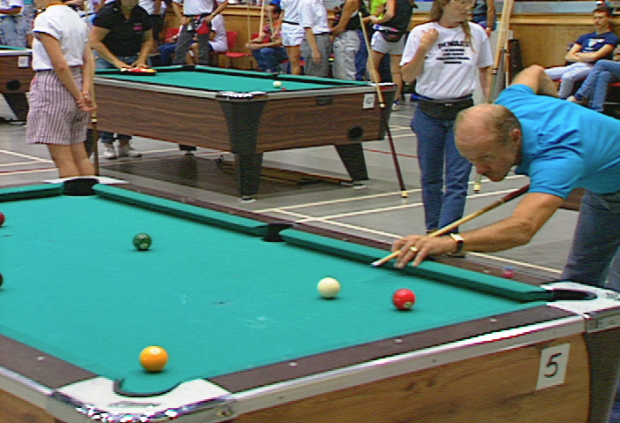 L'homme aligne un tir au concours de billard.