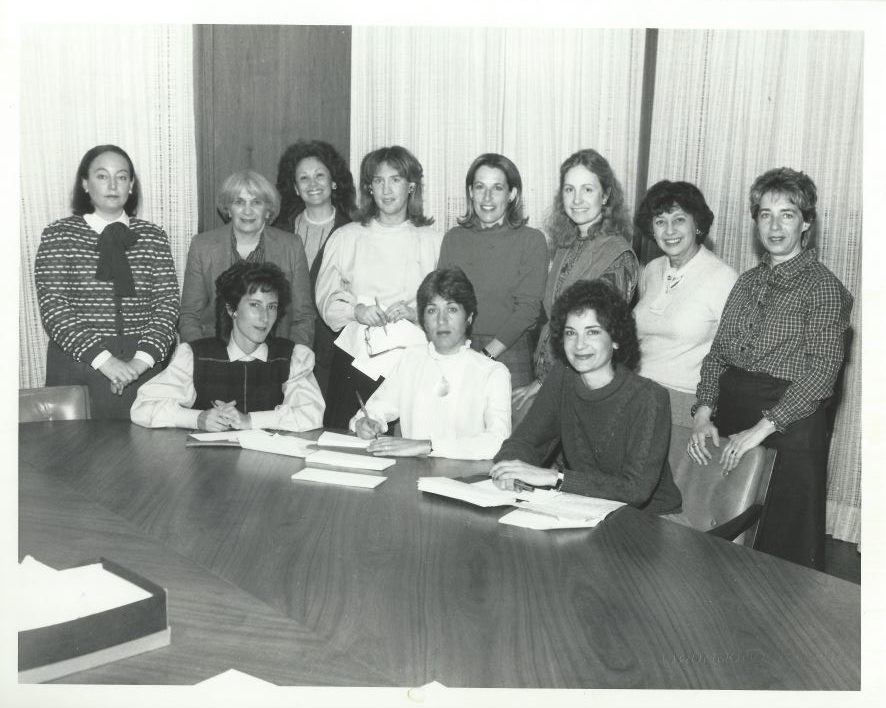Une photographie en noir et blanc d’un groupe de femmes autour d’une table.