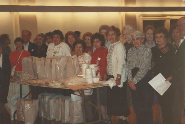 Un groupe de femmes de la confrérie sororale se tient autour d’une table remplie de repas à livrer.