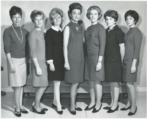 Une photographie formelle en noir et blanc d’un groupe de femme dans une tenue des années 1960.