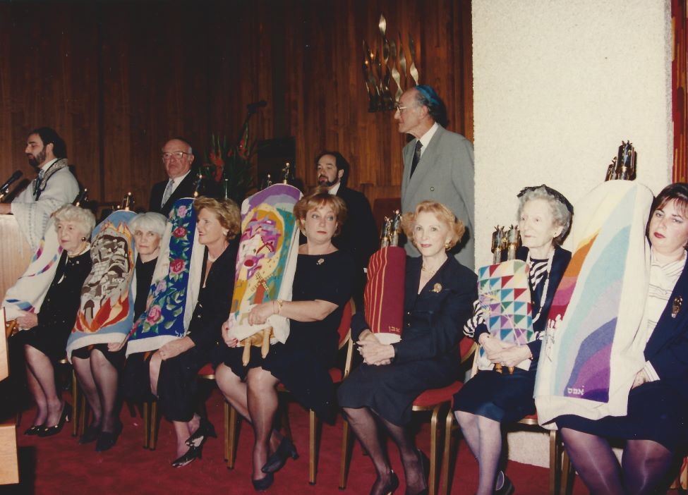 Un groupe de femmes assises tiennent des rouleaux de la Torah.