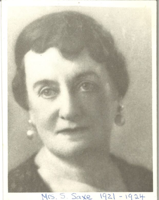 Une photographie en noir et blanc d’une femme d’âge moyen portant les cheveux relevés et des boucles d’oreille.