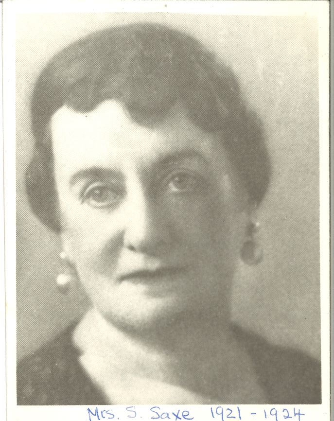 Une photographie en noir et blanc d’une femme d’âge moyen portant les cheveux relevés et des boucles d’oreille.