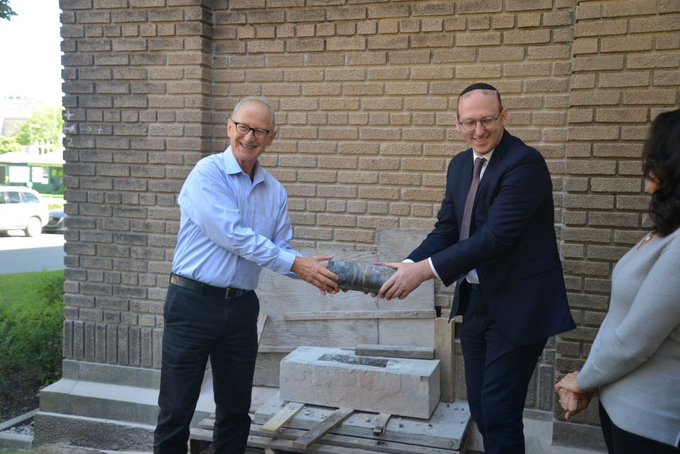 Deux hommes retirent une capsule temporelle de la pierre angulaire d’une synagogue.