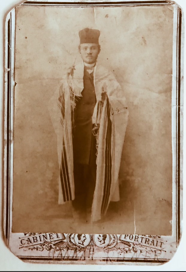 Photographie en noir et blanc d'un homme portant des robes de chantre et un châle de prière.