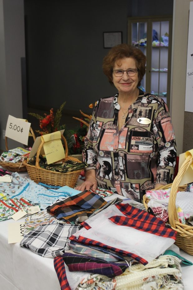 Une femme souriante est debout derrière une table sur laquelle sont déposés des sacs colorés en filet et en tissu pour les aliments en vrac. 