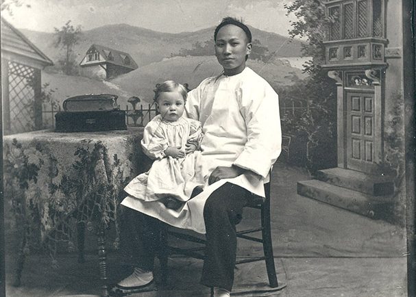  Employé de maison chinois posant pour un photographe, assis sur une chaise avec un jeune enfant sur le genou droit 