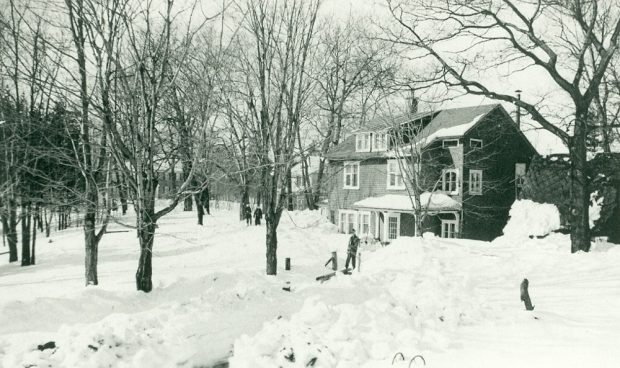 Photo d'une maison assise dans la neige avec un chemin vers la porte d'entrée