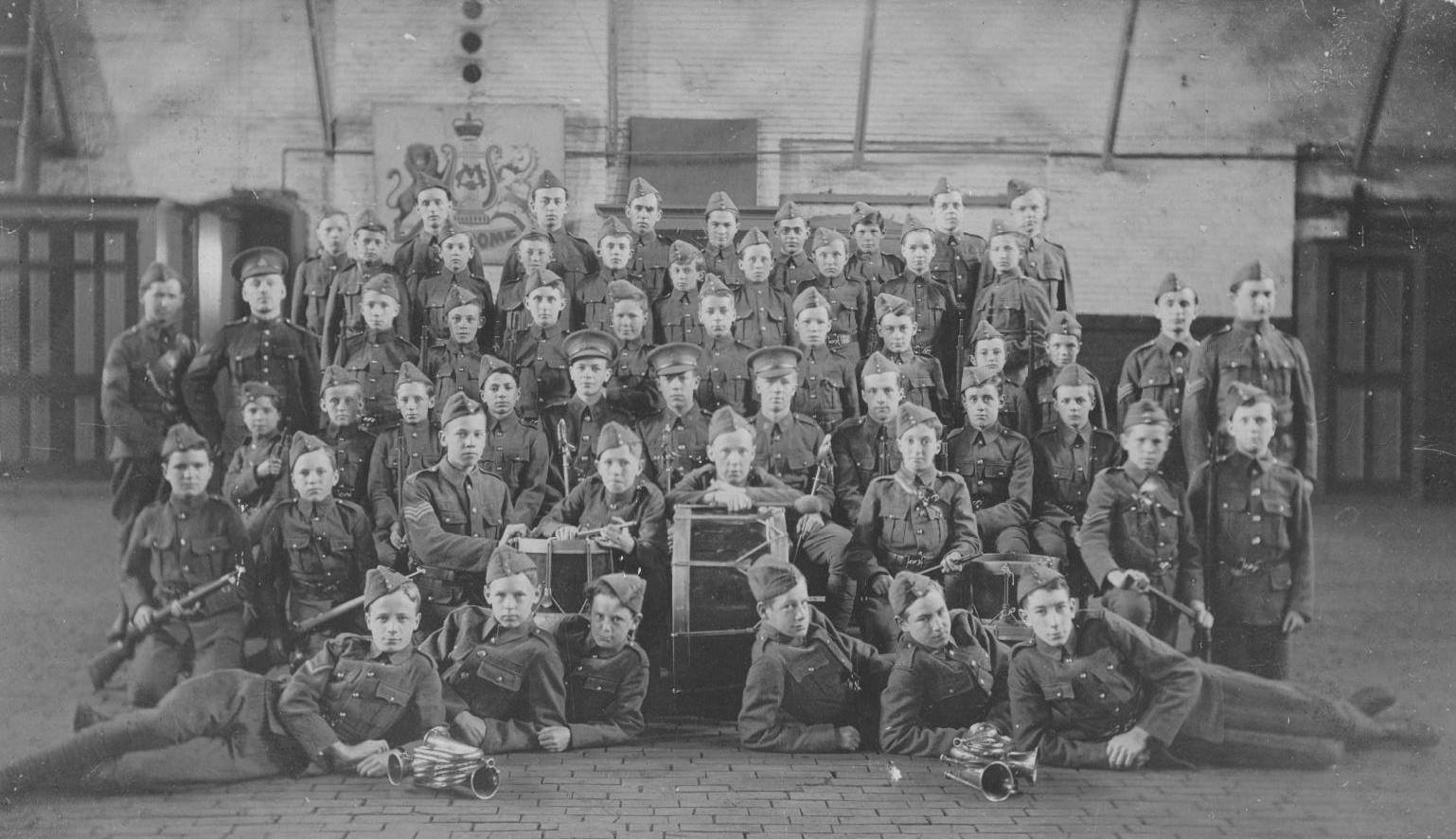 Photo noir et blanc d'un groupe de garçons vêtus d'un uniforme militaire debout dans un gymnase.