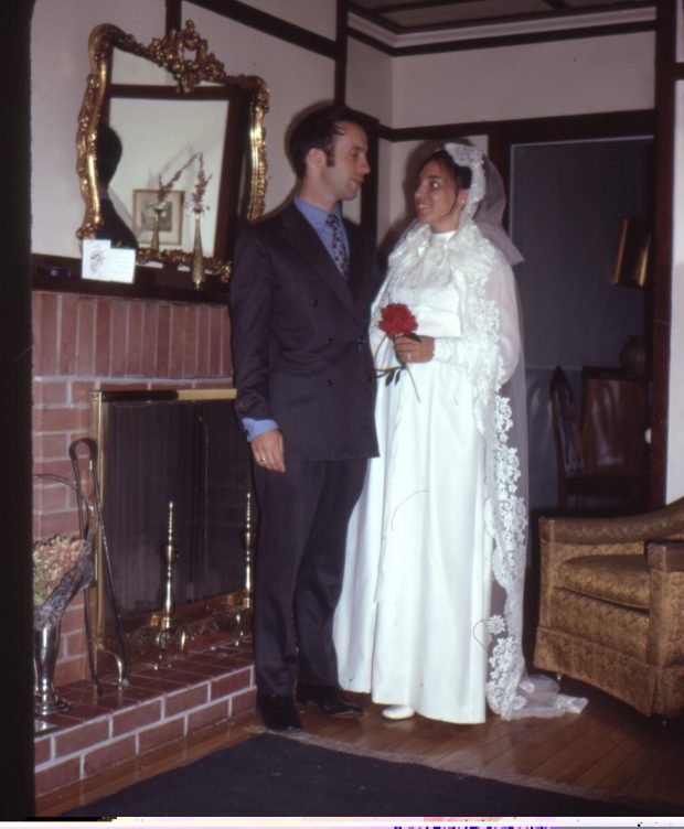 image couleur d'un homme et une femme habillée pour un mariage. Ils sont debout devant une cheminée.