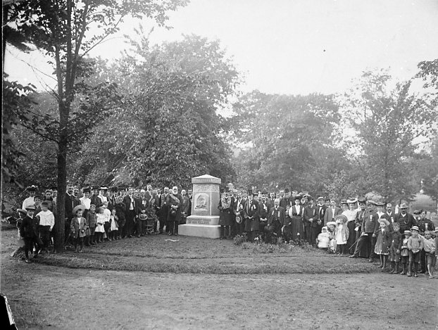 photo en noir et blanc d'un grand groupe de personnes autour d'un monument du cimetière pour une photo