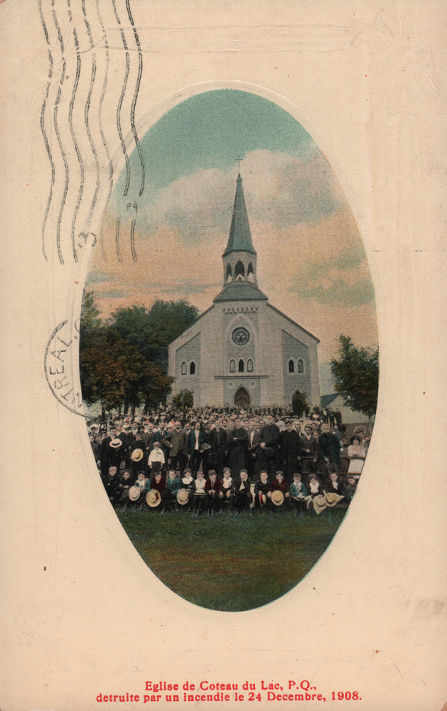 Photographie ancienne coloriée de forme ovale, plan éloigné, une foule prend la pose pour une photographie devant la façade d’une petite église blanche et bleue.