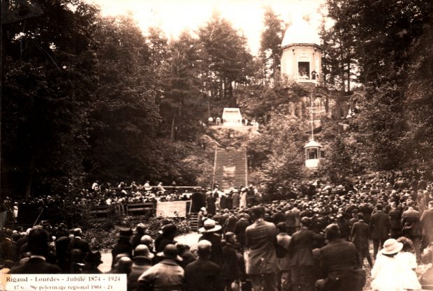 Photographie ancienne en noir et blanc, une foule est rassemblée au pied d’une colline surmontée d’une rotonde entourée d’arbres, au centre, un immense escalier.