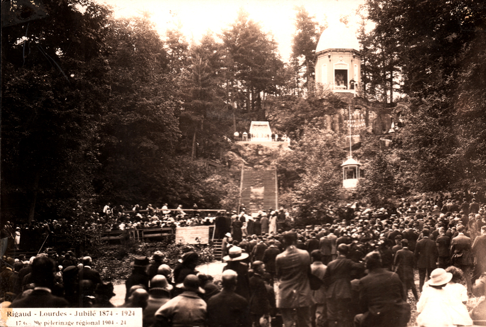 Photographie ancienne en noir et blanc, une foule est rassemblée au pied d’une colline surmontée d’une rotonde entourée d’arbres, au centre, un immense escalier.